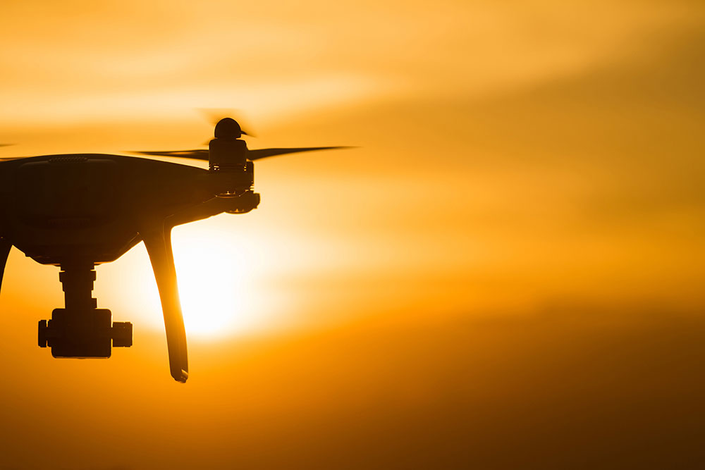 Air Drone with Action Cameras Flying in Dramatic Sunset Sky